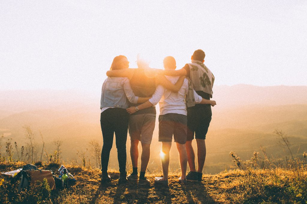 People holding each other on a montain looking into the distance